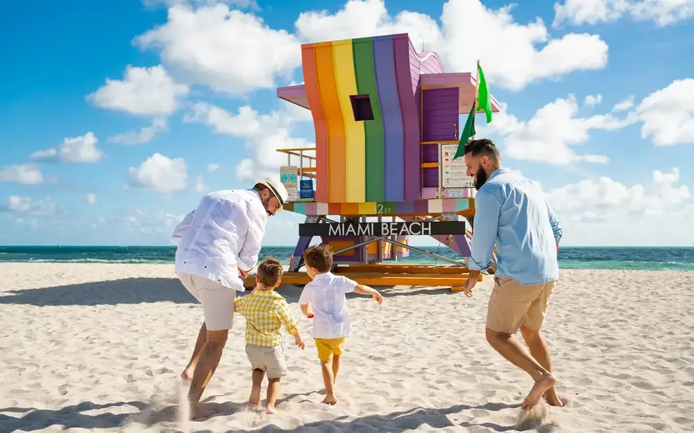LGBTQ family next to a rainbow lifeguard stand on Miami Beach