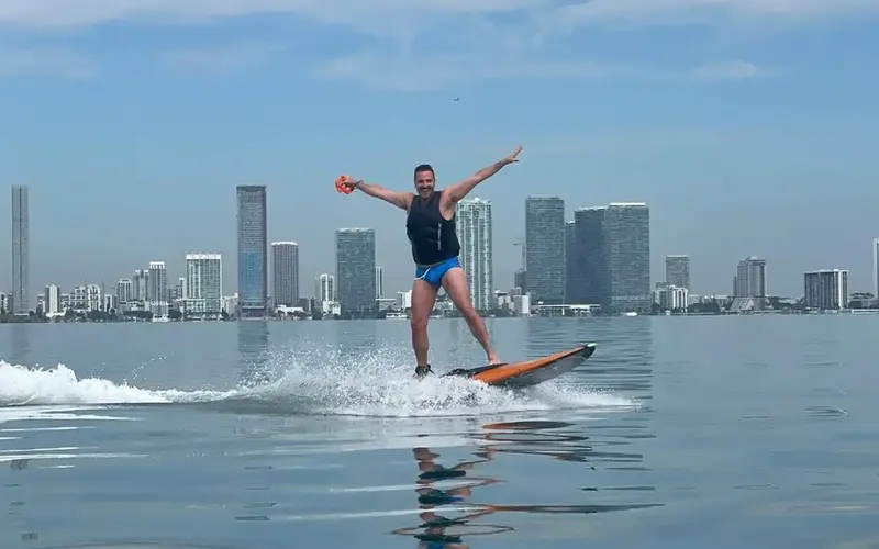 Ravi Roth surfing with a view of the Downtown Miami skyline