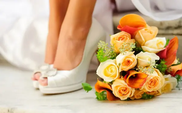 Elegant wedding shoes and bridal bouquet with roses