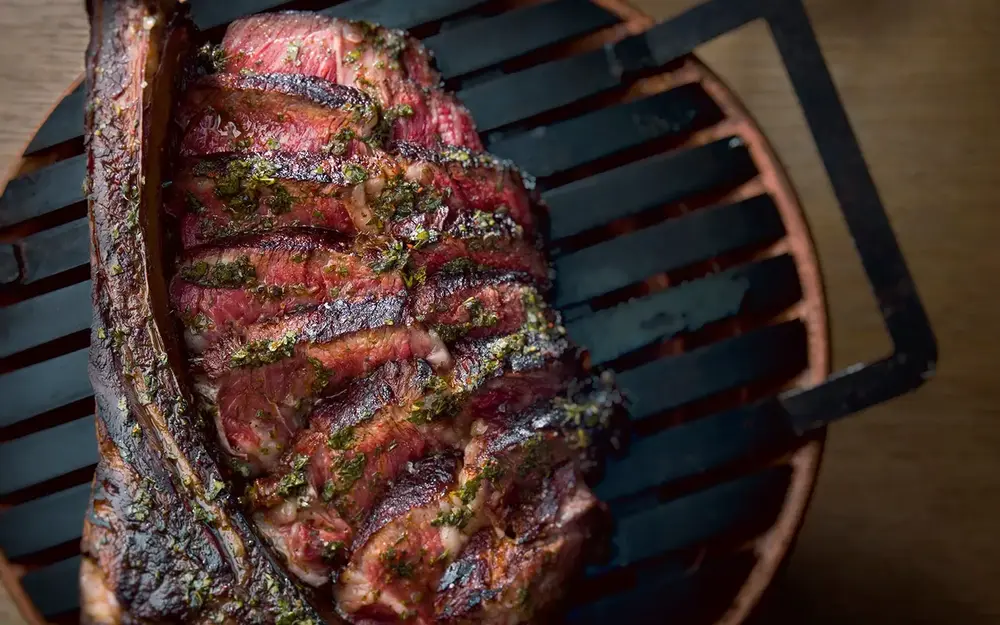 Los Fuegos ribeye steak over a grill