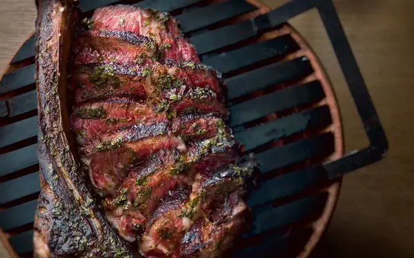 Los Fuegos ribeye steak over a grill
