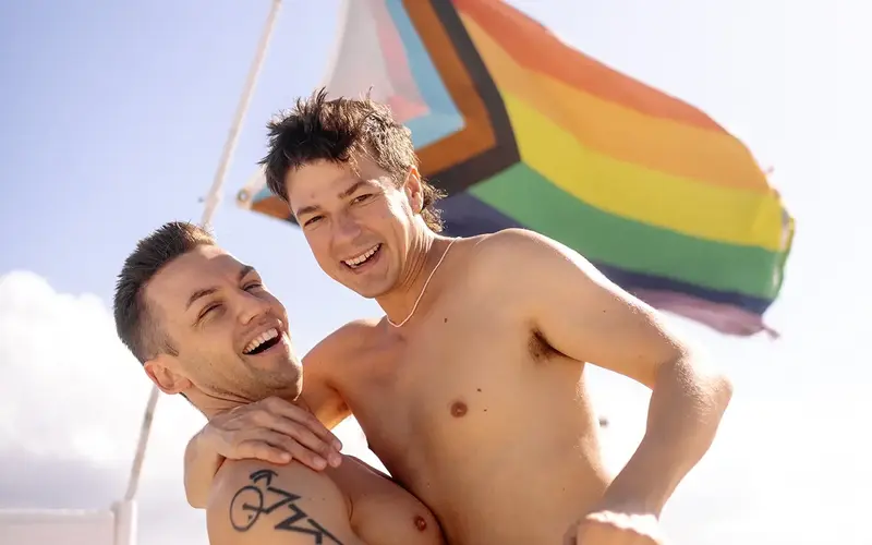 Matt and Michael standing in front of a flag at the beach