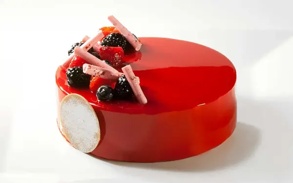 Bachour's entremet with a bright red mirror glaze and berries on top