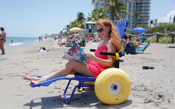Woman on the beach, sitting on a Joy on the Beach wheelchair