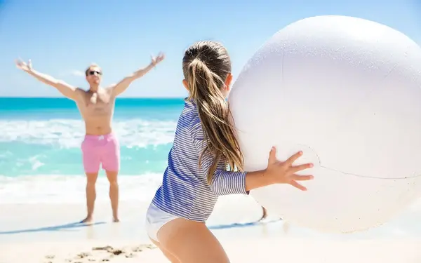 Father and daughter playing with a ball on the beach