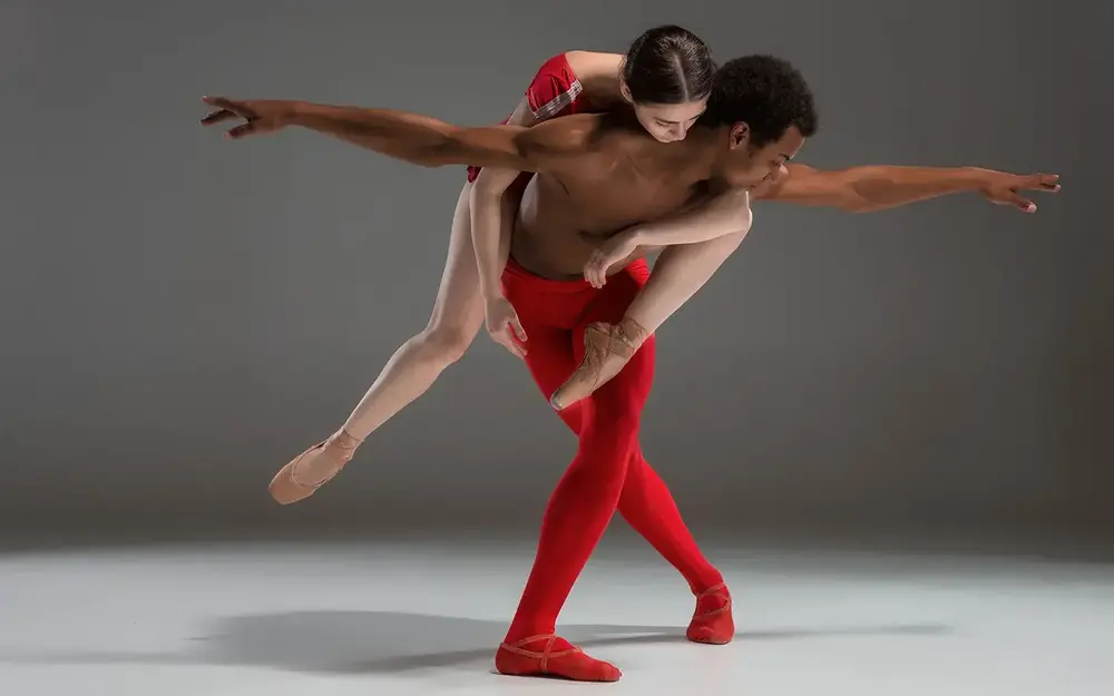 Ballet dancing couple in red, with woman on man's back