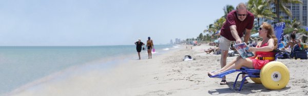 Donna sulla spiaggia, seduta su una gioia sul Beach Sedia a rotelle