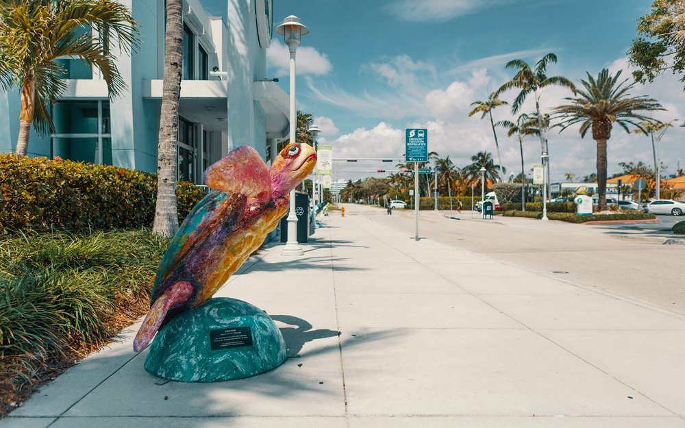 Escultura de tortuga colorida gigante que adorna la acera en Surfside