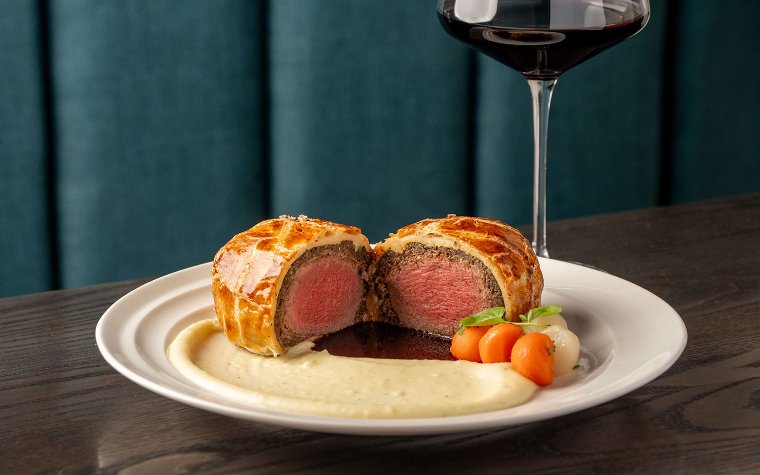 Beef Wellington at Hell's Kitchen with flaky crust, beef, vegetables, and mashed potatoes