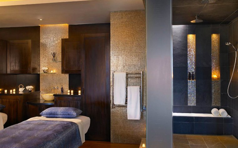 Massageraum im Acqualina Spa zeigt Massagetisch und Duschbereich