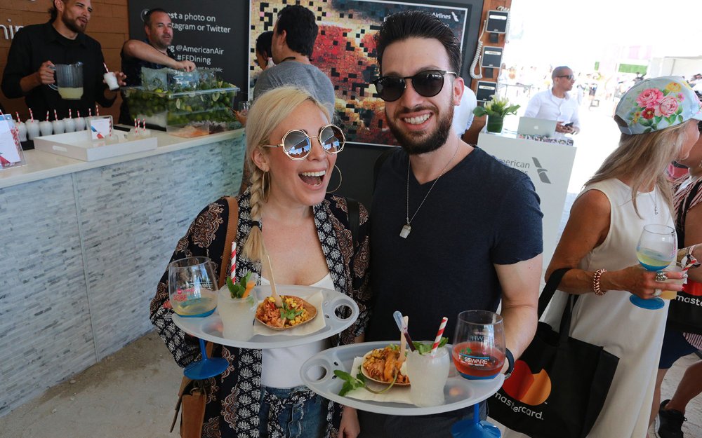 Couple holding trays with food samples