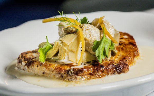 Isabella restaurant’s parmesan-crusted swordfish plated with garnish.