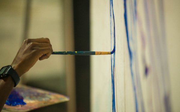 Imagen de una mano sujetando un pincel para el dolor sobre un lienzo