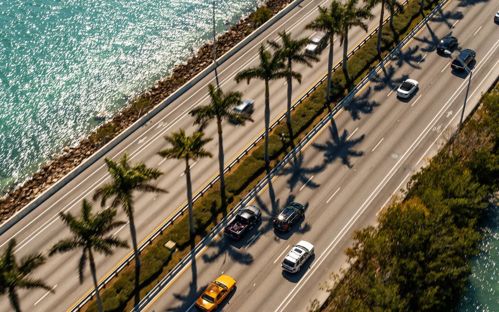 Aerial view of MacArthur Causeway with palm trees, cars and blue ocean