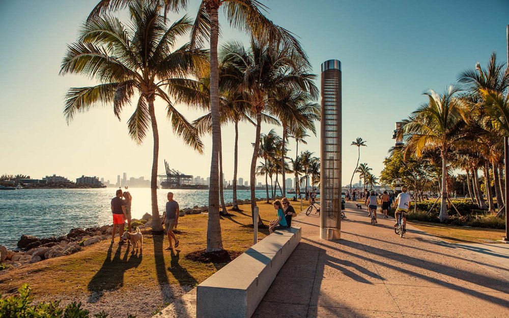 Ruta escénica en South Point Park, Miami Beach , con personas y perros, palmeras y vistas al mar.