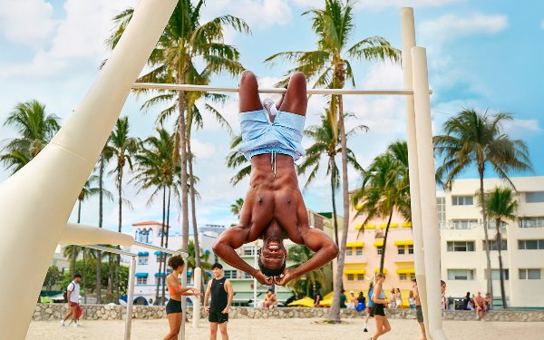 Man hanging on a gymnastics bar in Lummus Park