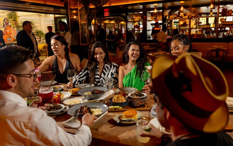 Group of Friends sitting around a table enjoying soul food dinner at the Red Rooster Group of Friends sitting around a table enjoying soul food dinner at the Red Rooster
