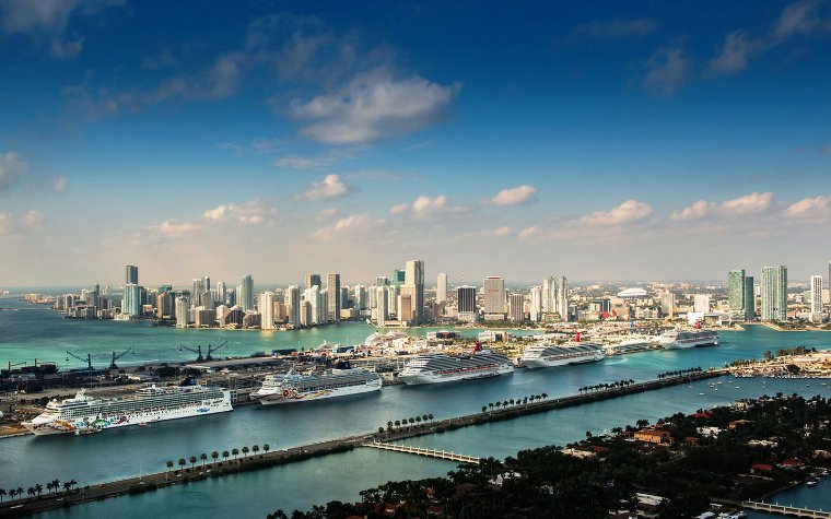 Cruise ships docked at PortMiami with the Miami skyline in the background Cruise ships docked at PortMiami with the Miami skyline in the background