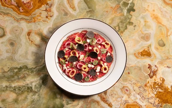 Delilah wagyu carpaccio artfully plated with fresh herbs