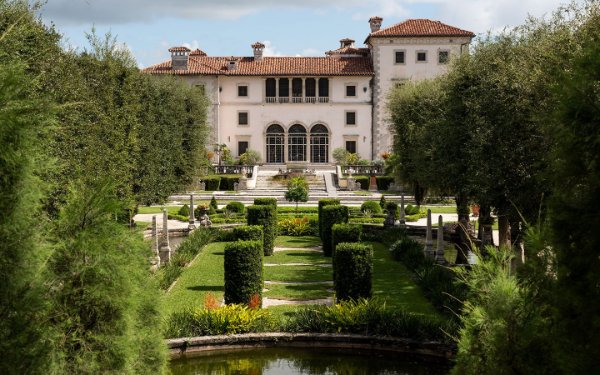 Uma visão serena de Vizcaya Museum & Gardens de dentro de seus exuberantes jardins, capturando a essência de seu charme histórico em meio à folhagem verdejante