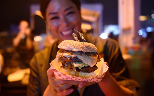 Woman holding a hamburger at SOBEWFF