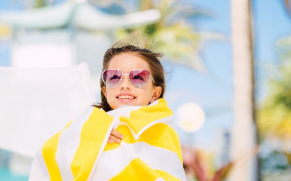 Little girl wearing sunglasses and wrapped in a beach towel