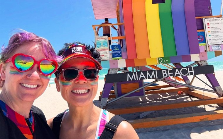 Rainbow lifeguard stand with two people standing in front on the beach Rainbow lifeguard stand with two people standing in front on the beach