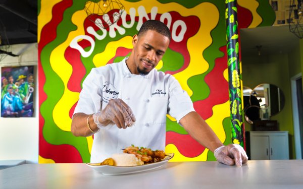 Chef mete dènye manyen sou yon plat nan Dukunoo Jamaican Kitchen