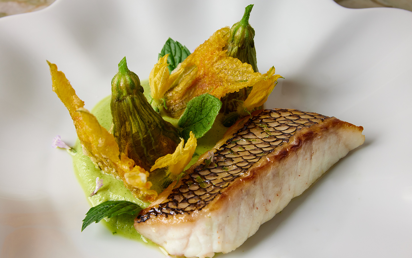 Herb-garnished seabass paired with colorful garden vegetables Herb-garnished seabass paired with colorful garden vegetables