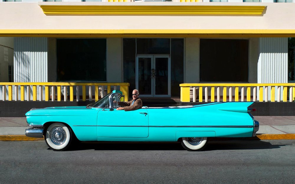 Uomo più anziano in Cadillac decappottabile parcheggiato di fronte a The Leslie Hotel Su South Beach