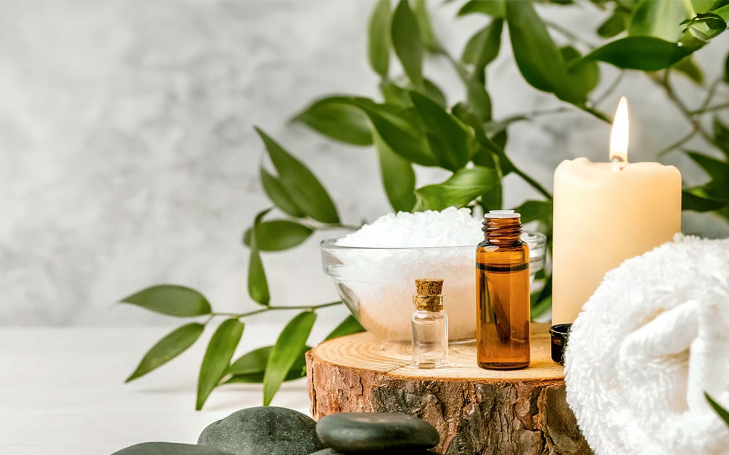 Ein Spa-Behandlungsambiente mit Duftkerzen, glatten Steinen und Flaschen mit wohltuenden Aromatherapie-Ölen