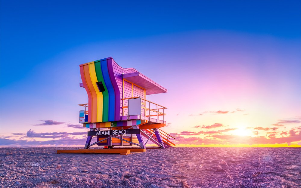 LGBTQ Flag flying in blue skies with bright sun shining through