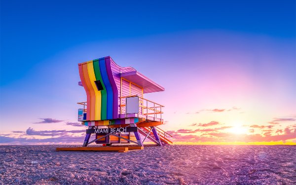 LGBTQ Flag flying in blue skies with bright sun shining through