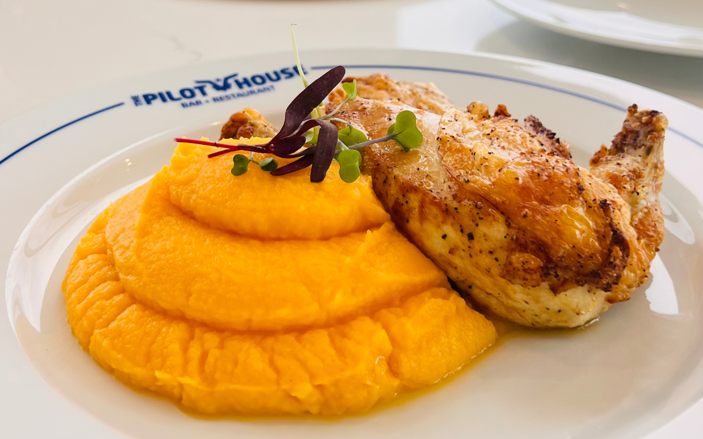 The Pilot House chicken, a plated dish featuring roasted chicken with crispy skin, garnished with fresh herbs and sides The Pilot House chicken, a plated dish featuring roasted chicken with crispy skin, garnished with fresh herbs and sides