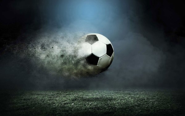 Футбольный мяч в движении над травянистой территорией