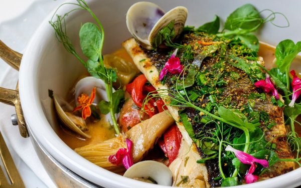 Clam dish topped with decorative magenta flowers at Fiola Miami