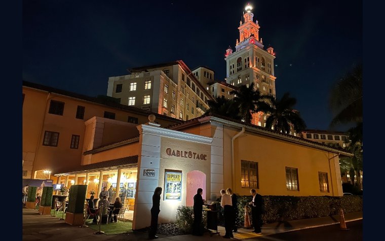 People standing outside at GableStage in the evening The Biltmore Hotel lit up in the background
