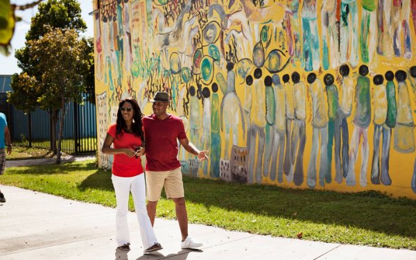 一对夫妇在 Overtown 的 Purvis Young 壁画旁散步