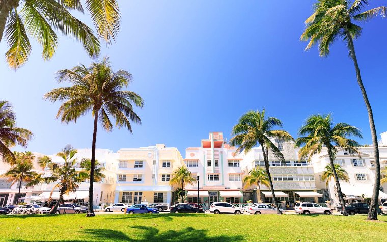 View of Ocean Drive with buildings, cars, and people enjoying lunch at outdoor cafes View of Ocean Drive with buildings, cars, and people enjoying lunch at outdoor cafes