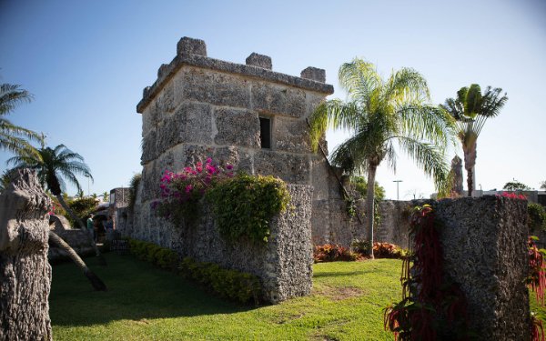 Coral Castle tower made completely out of coral rock with blue sky and palm trees