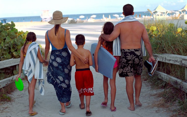 Family walking with beach towels into the entrance of Miami Beach Family walking with beach towels into the entrance of Miami Beach