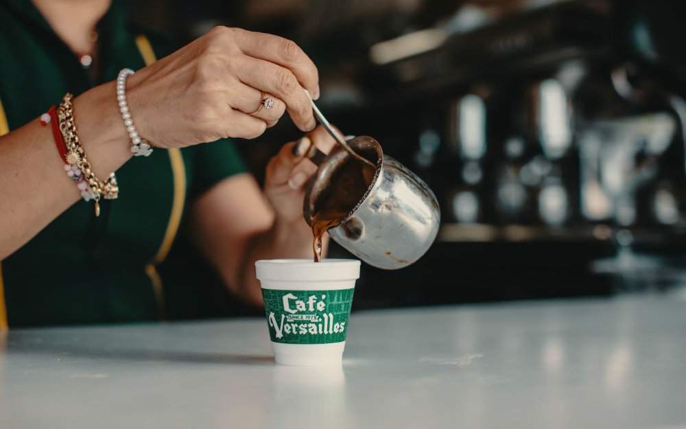 Café cubano que está sendo derramado em um copo em Versailles Restaurant