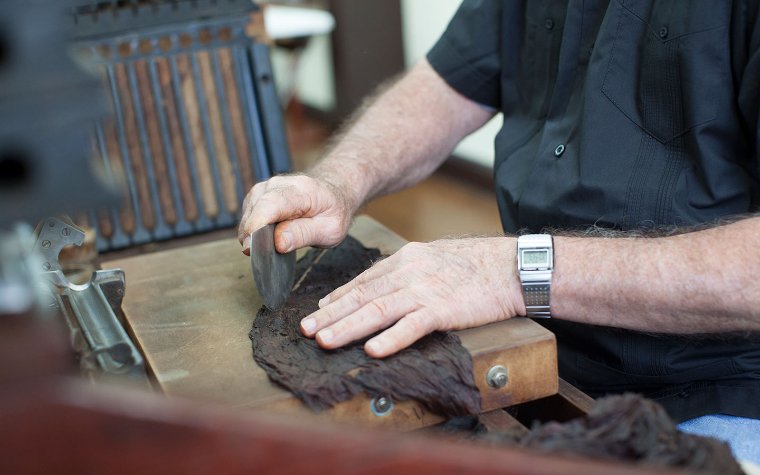 Man preparing to roll a cigar by hand Man preparing to roll a cigar by hand